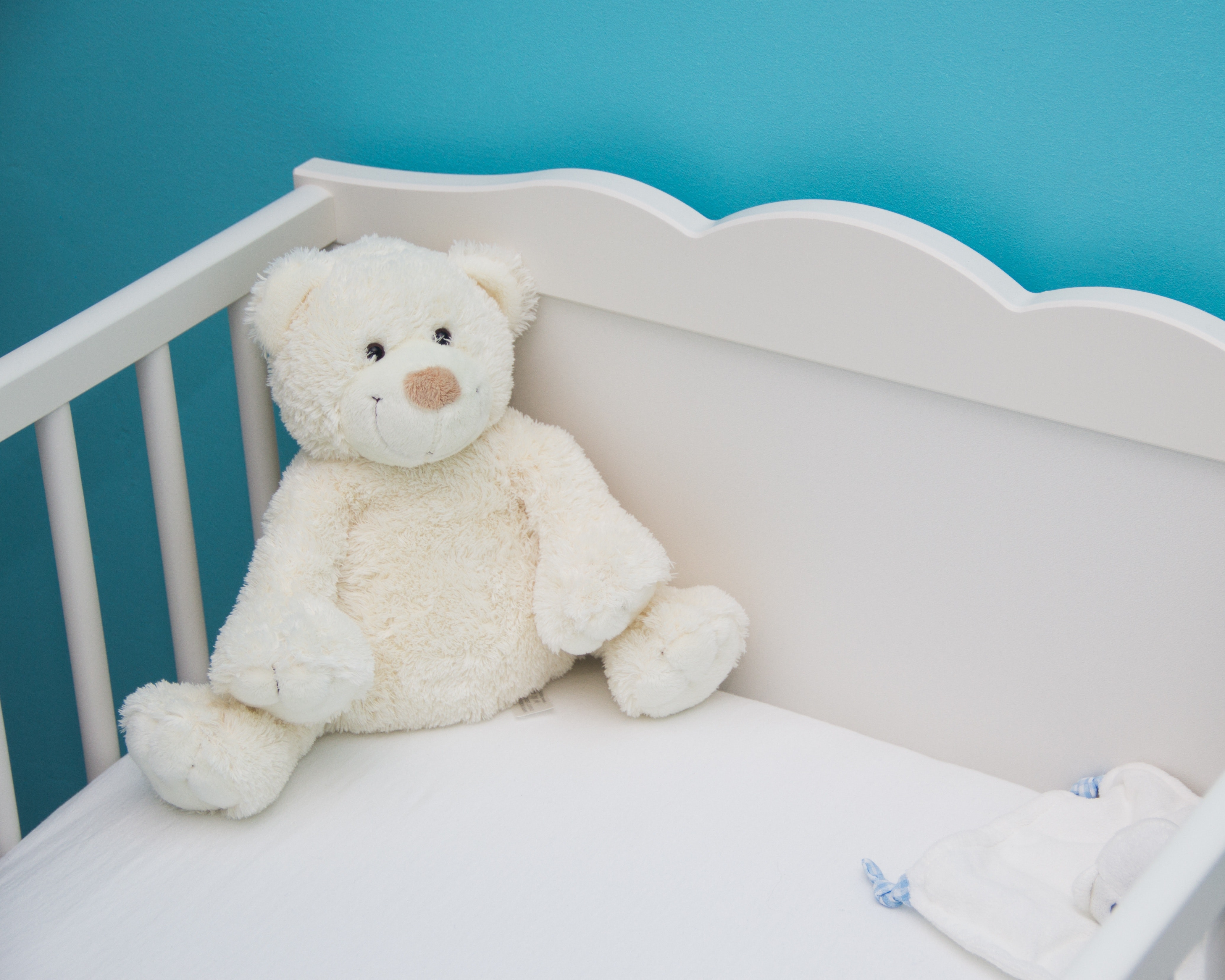 Teddy bear sitting in cot