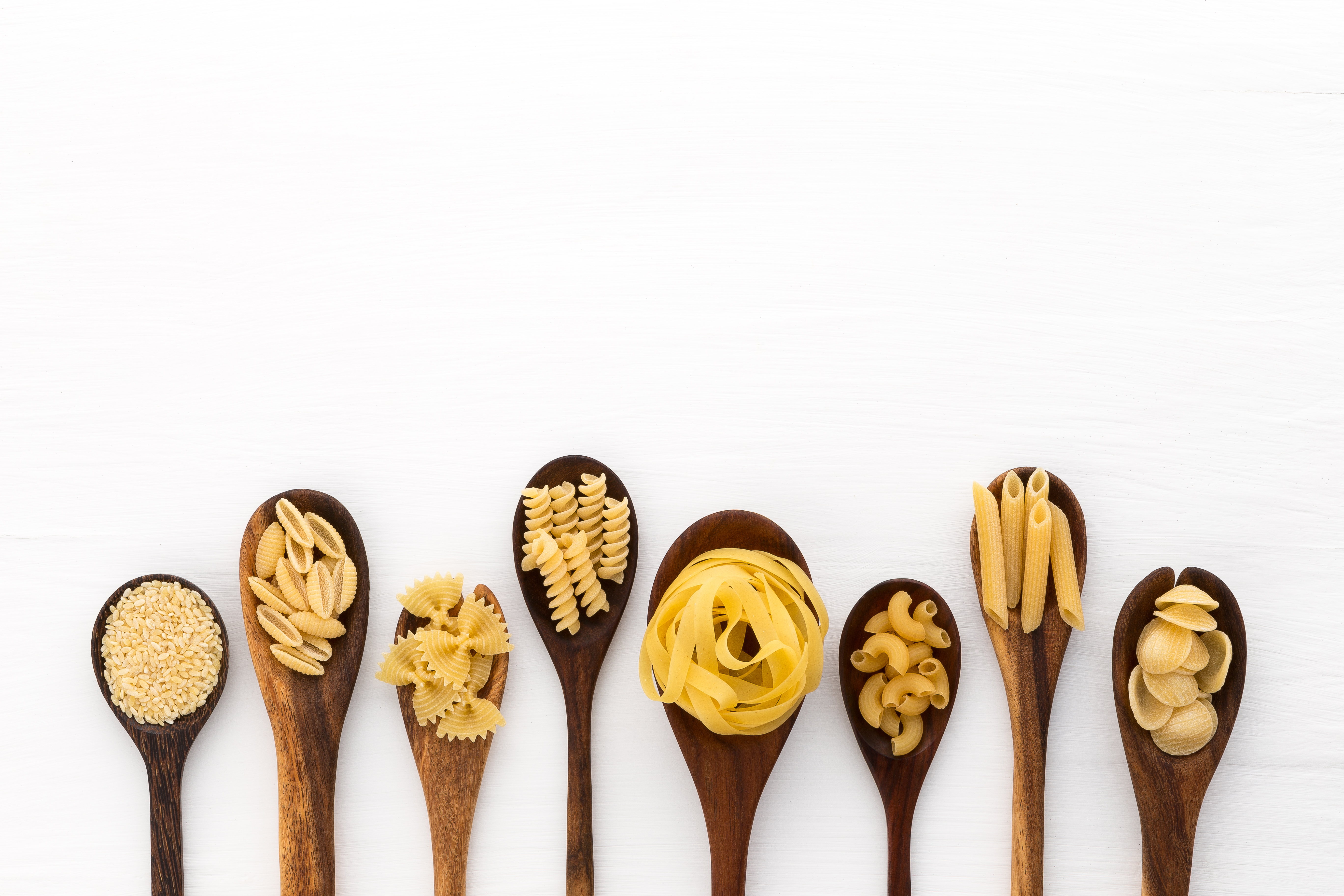 Different types of pasta on wooden spoons